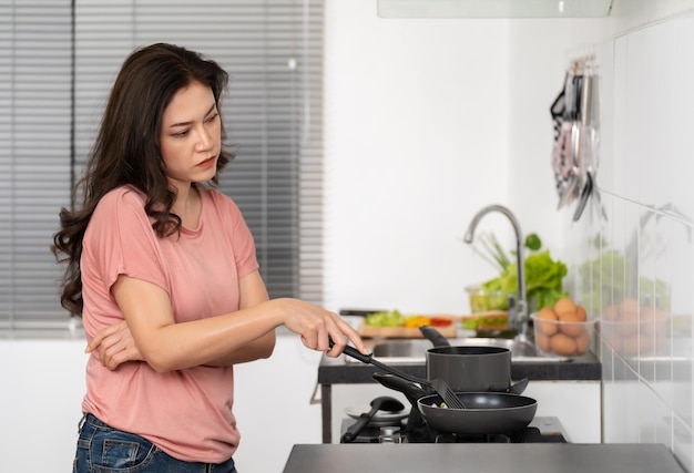 Femme fatiguée faisant cuire et préparant la nourriture dans la cuisine à la maison