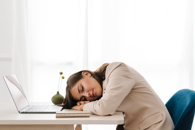 Femme fatiguée faisant la sieste sur son ordinateur portable