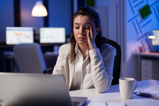 Une femme fatiguée s'endort en vérifiant l'analyse financière tard dans la nuit dans un bureau d'affaires