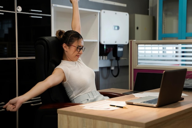 Photo femme fatiguée tordant et déplaçant les muscles pour soulager les maux de dos dans les articulations de l'épaule après avoir travaillé longtemps devant l'ordinateur