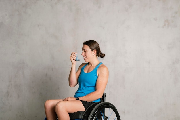 Femme en fauteuil roulant à l'aide d'un inhalateur pour l'asthme