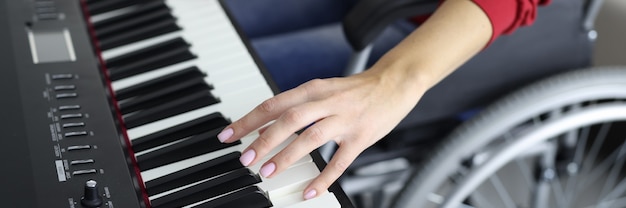 Femme en fauteuil roulant appuie sur les touches du piano close-up