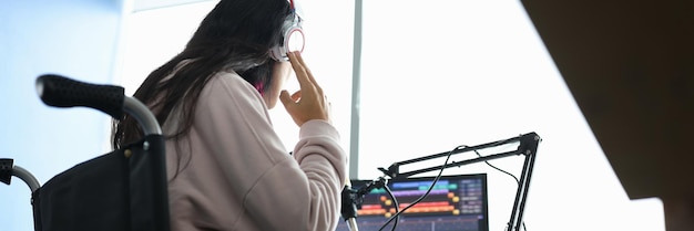 Femme en fauteuil roulant avec un casque devant le microphone et les flux informatiques de passage