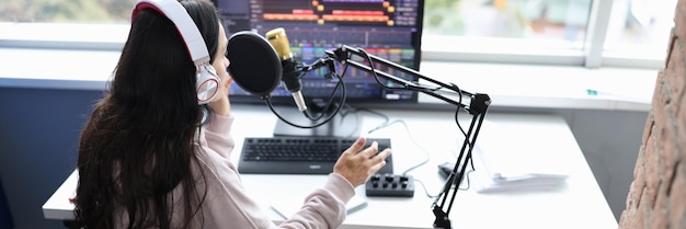 Une femme en fauteuil roulant avec un casque parle dans un microphone devant un écran d'ordinateur