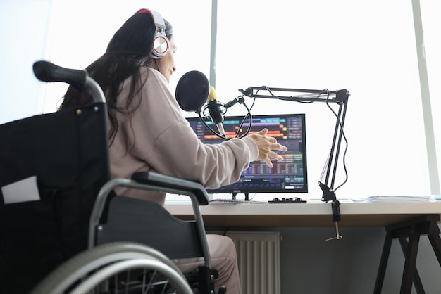 Une femme en fauteuil roulant parle dans un microphone devant un ordinateur de travail à distance pour les personnes handicapées