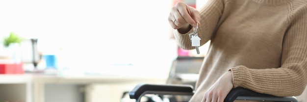 Femme en fauteuil roulant tenant la clé de l'appartement libre