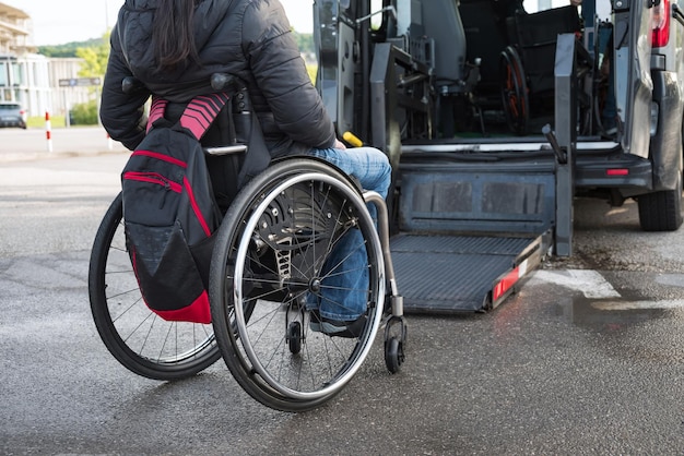 Femme en fauteuil roulant utilisant un ascenseur de voiture accessible aux personnes handicapées