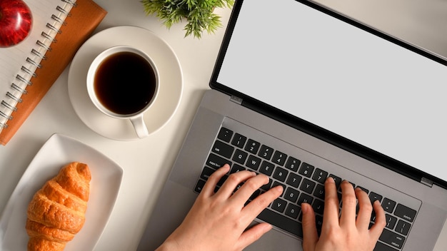 Une femme ou une femme d'affaires travaillant sur un ordinateur portable dans la vue de dessus de son espace de travail moderne