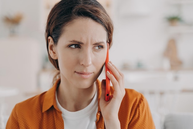 Une femme ou une femme inquiète a un appel Une jeune femme anxieuse tient un téléphone et parle à la maison