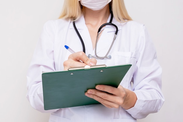 Photo femme femme médecin écrit sur le presse-papiers un diagnostic et une prescription après examen d'un patient