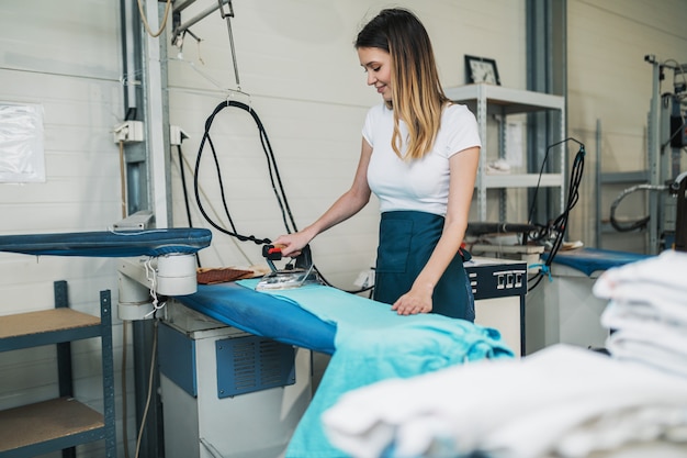 Femme Avec Fer Travaillant à L'atelier De Repassage. Services De Nettoyage.