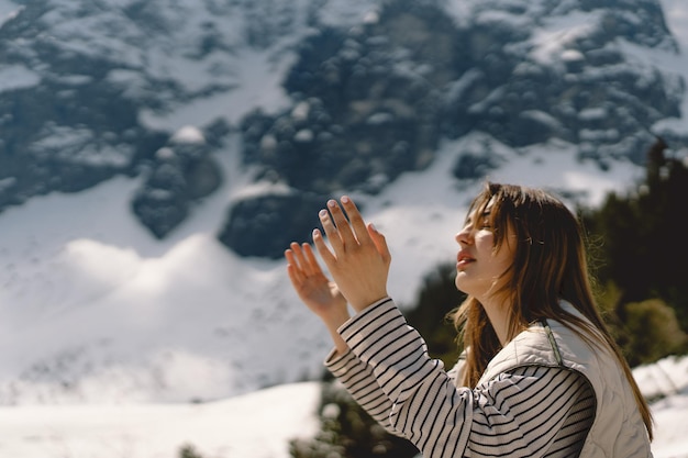 Femme ferma les yeux en priant près de la montagne Mains jointes dans le concept de prière pour la foi, la spiritualité et la religion Concept de rêves d'espoir de paix