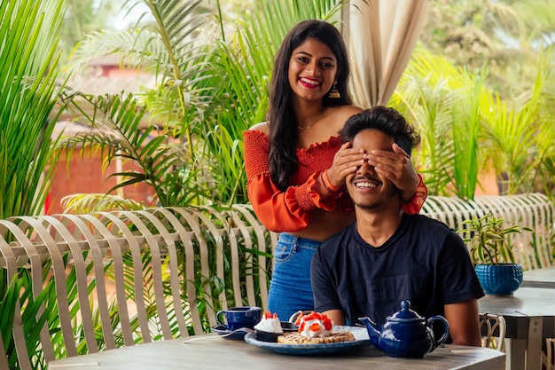 Femme fermant les yeux de son petit ami pour faire la surprise au restaurant été tropical café plage urbaine Saint Valentin 14 février