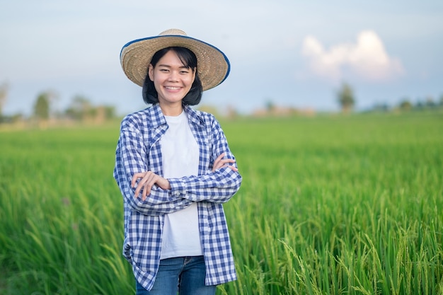 Femme fermière sourire et croiser les mains debout dans une ferme de riz vert