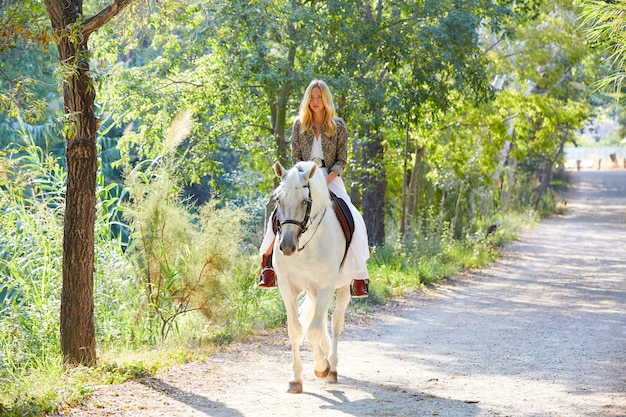 Femme fille blonde chevauchant un cheval en piste