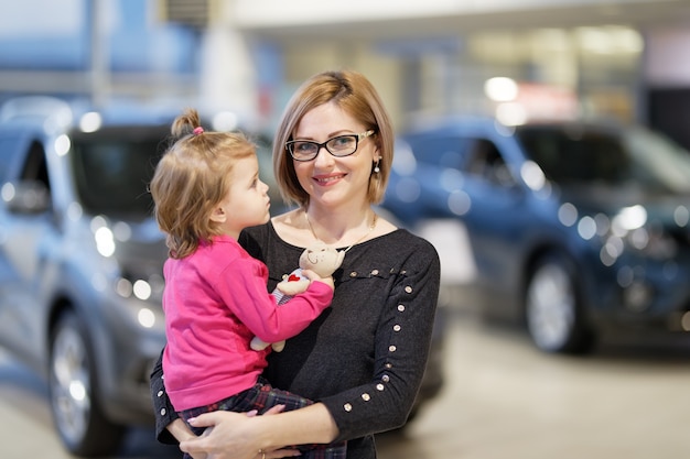 Femme avec fille choisir une voiture en concession