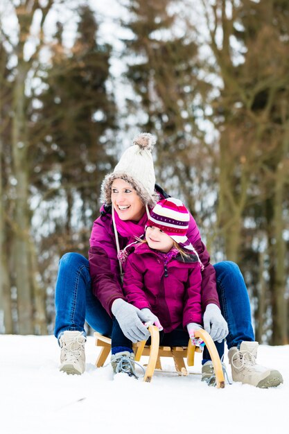 Femme et fille sur un traîneau en hiver