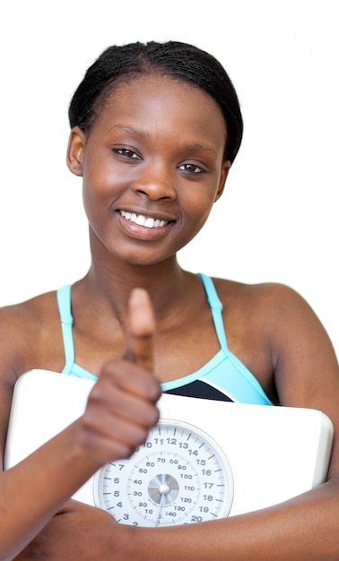 Photo femme de fitness de charme avec le pouce en haut tenant une échelle de poids