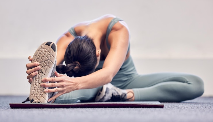 Photo femme fitness ou jambes qui s'étirent sur un tapis lors d'une séance d'entraînement en salle de sport ou d'un exercice pour soulager la tension musculaire ou bien-être pour la santé du corps athlète sportif entraîneur personnel ou entraîneur en échauffement au sol