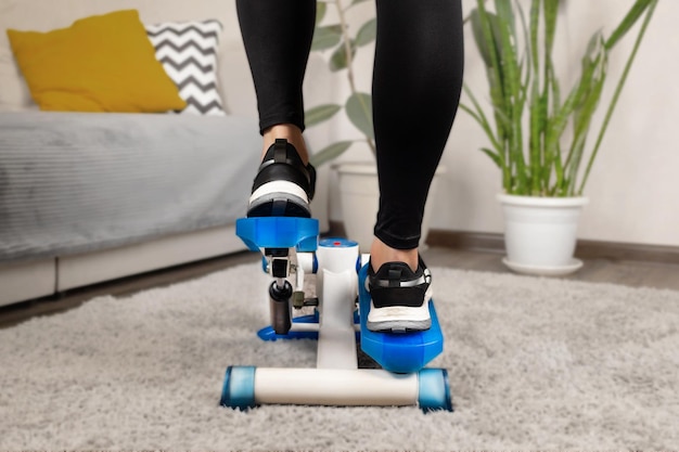 Photo une femme de fitness à la maison fait des exercices sur un stepper à la maison en gros plan