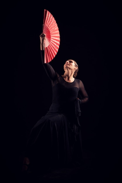 Femme de flamenco avec robe noire et éventail rouge en levant