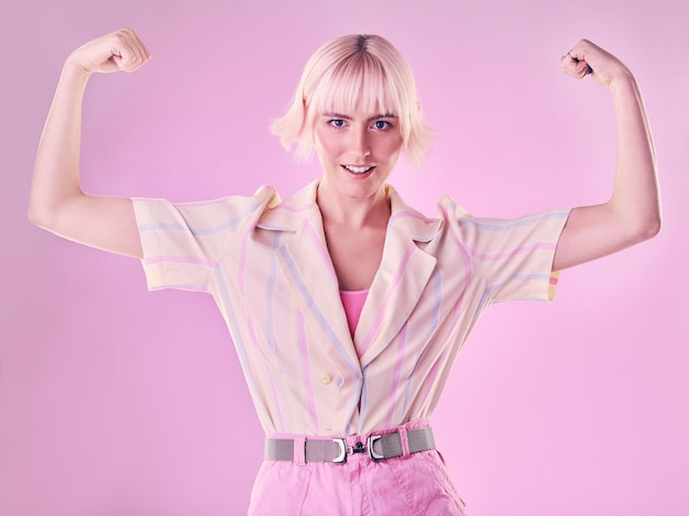 Femme fléchissant le muscle du bras dans le portrait et la puissance du sourire et une femme forte isolée sur fond rose Liberté combat l'autonomisation et la force avec confiance fierté dans le défi avec le champion et la victoire