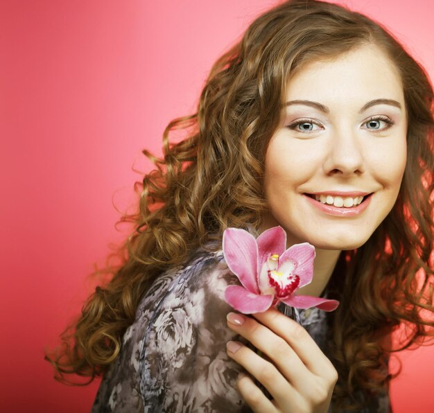 Femme avec fleur d'orchidée sur fond rose