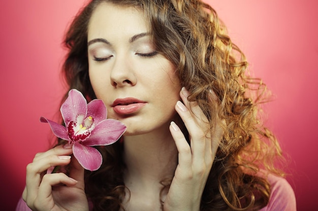 Femme avec fleur d'orchidée sur fond rose