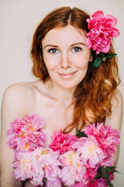 Une femme avec une fleur de pivoine dans ses cheveux.