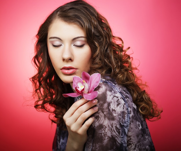 Femme avec fleur rose sur fond rose