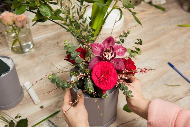 Femme fleuriste mains organisant la composition florale