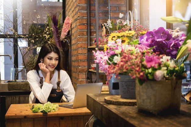 Femme fleuriste regardant un ordinateur portable a obtenu l&#39;ordre au comptoir de son fleuriste