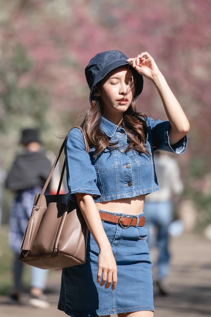 Femme avec des fleurs de cerisier ou une fleur de sakura qui fleurit dans le parc