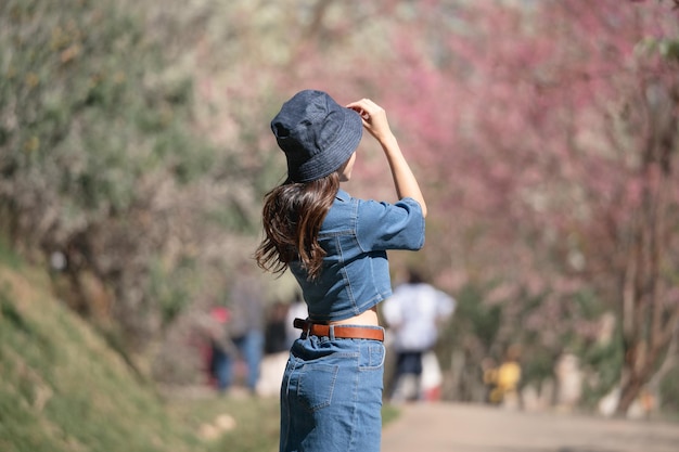 Femme avec des fleurs de cerisier ou une fleur de sakura qui fleurit dans le parc