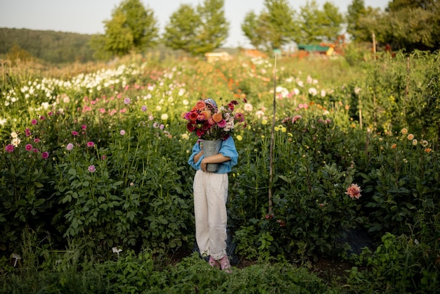 Femme avec des fleurs sur la ferme de dahlia à l'extérieur