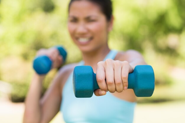 Femme floue, exercice avec des haltères dans le parc