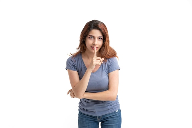 Femme sur fond blanc demandant le silence avec son doigt