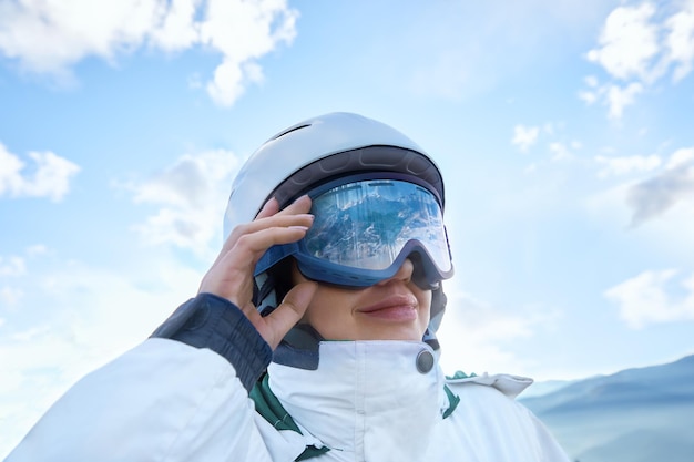 Femme sur le fond Blue SkySki Goggles d'une fille avec le reflet de montagnes enneigées portant des lunettes de ski Sports d'hiver