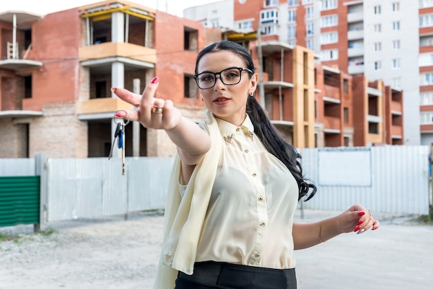 Femme sur fond de chantier avec les clés de l'appartement