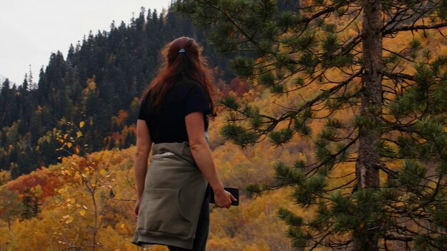 Femme sur fond de forêt d'automne jaune, collines boisées créatives et concept de randonneuse féminine