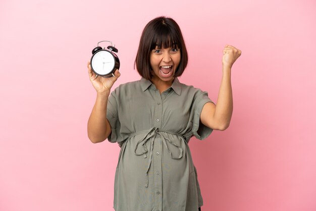 Femme sur fond isolé enceinte et tenant l'horloge