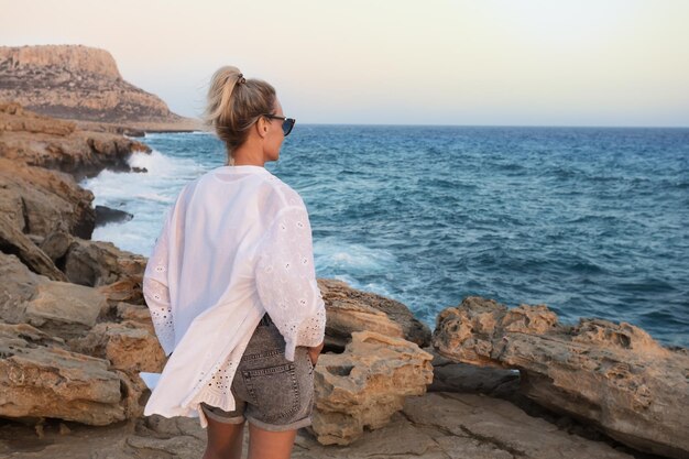 Femme sur le fond de la mer coucher de soleil Profiter de la vie et regarder la mer Vacances d'été Chypre