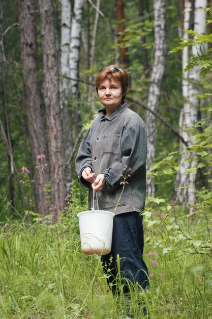 Femme en forêt avec godet - ramasser des champignons, téléobjectif