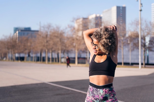 Femme en forme africaine qui s'étend dans un parc urbain