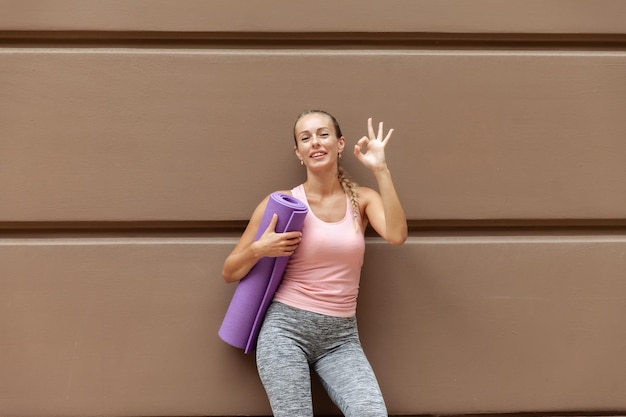 Photo une femme en forme joyeuse avec du yoga posant près du mur à l'extérieur
