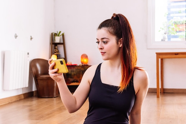 Femme de forme physique s'asseyant et à l'aide du téléphone portable