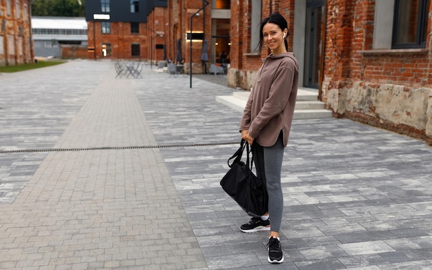 Femme de forme physique avec un sac de sports posant sur la ville après le gymnase