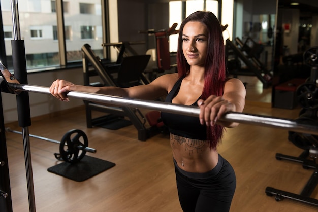 Femme de forme physique se préparant à exercer des jambes à l'intérieur de gymnase