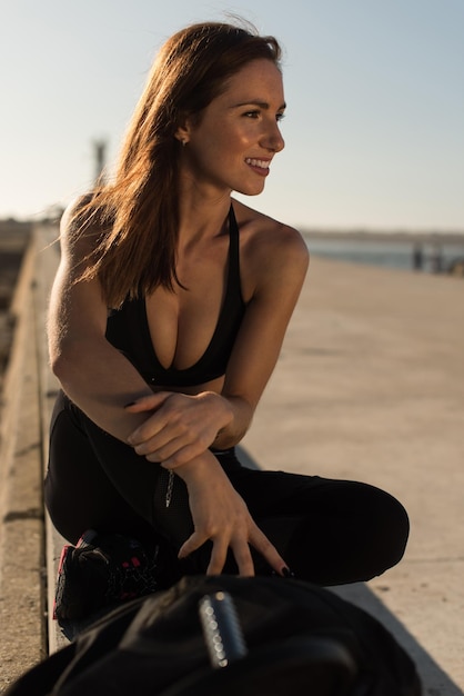 Femme en forme profitant du coucher de soleil après une séance d'entraînement en plein air avec des poids