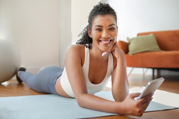 Une femme en forme qui utilise son application d'entraînement sur son téléphone portable à la maison